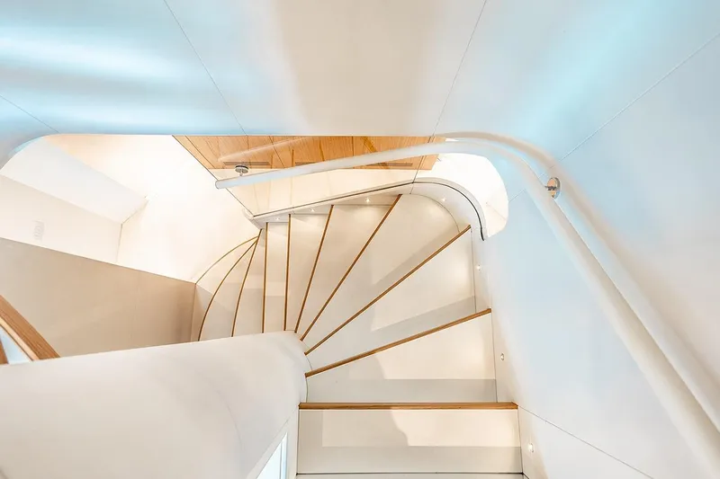 Koju Yacht Photos Pics Elegant spiral staircase on 2022 Benetti Motopanfilo yacht, featuring sleek white and wood design.