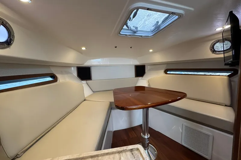  Yacht Photos Pics 2018 Pursuit OS 325 Offshore cabin interior with seating and wooden table.