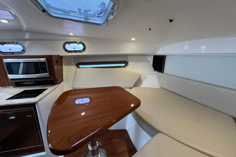  Yacht Photos Pics 2018 Pursuit OS 325 Offshore cabin interior with seating, table, and kitchenette.