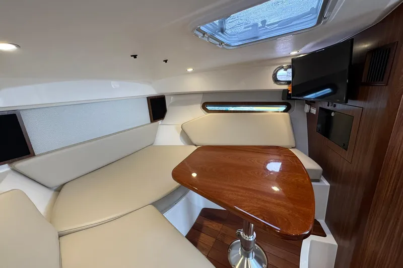  Yacht Photos Pics 2018 Pursuit OS 325 Offshore cabin interior with seating, table, and TV.