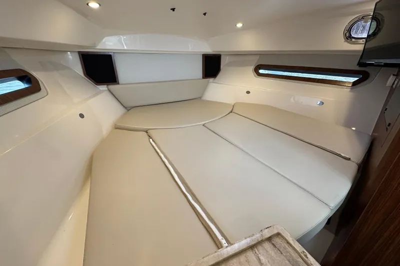  Yacht Photos Pics 2018 Pursuit OS 325 Offshore cabin interior with beige seating and porthole windows.