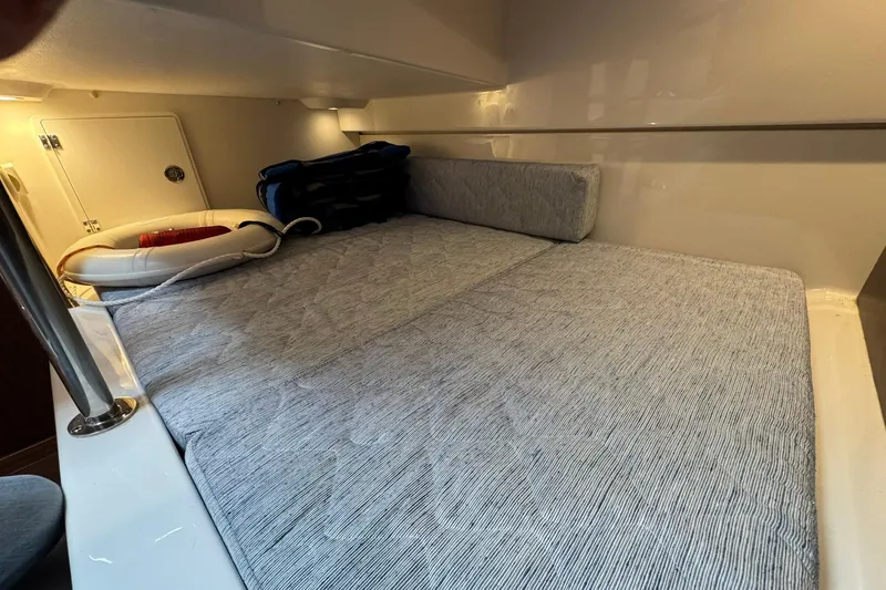  Yacht Photos Pics 2018 Pursuit OS 325 Offshore cabin interior with cushioned bed and storage space.