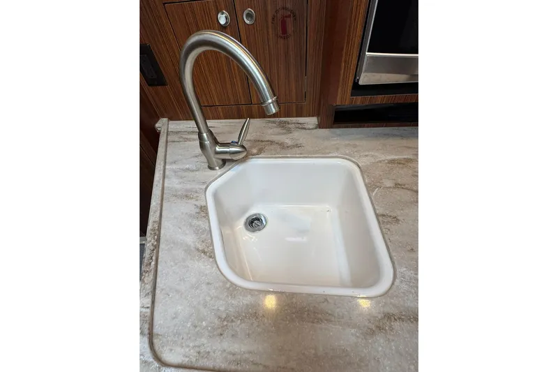 Yacht Photos Pics Stainless steel faucet and white sink in 2018 Pursuit OS 325 Offshore boat kitchen.