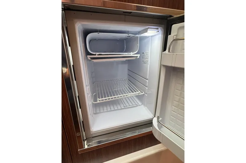  Yacht Photos Pics Open refrigerator inside 2018 Pursuit OS 325 Offshore boat, showing empty shelves.