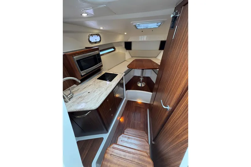  Yacht Photos Pics 2018 Pursuit OS 325 Offshore cabin interior with kitchenette and seating area.