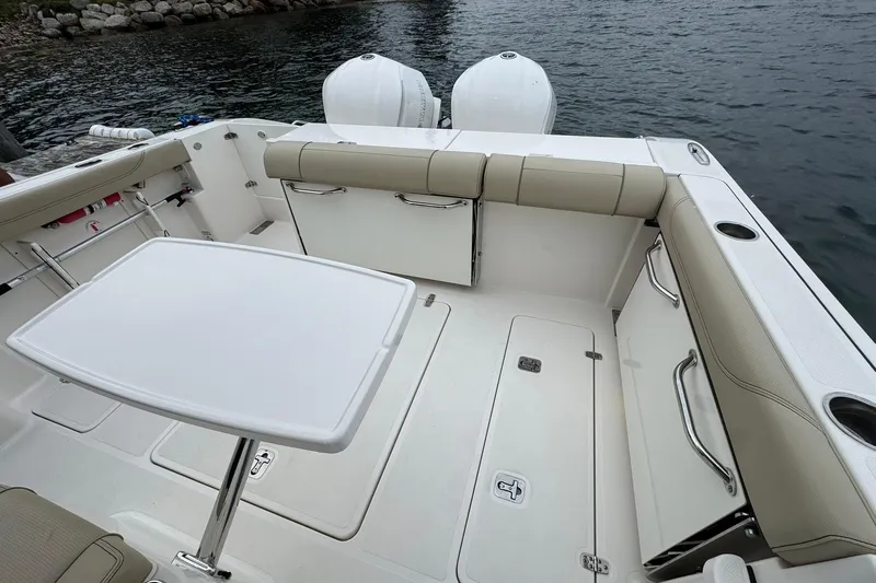  Yacht Photos Pics 2018 Pursuit OS 325 Offshore boat interior with seating and table, docked by the water.