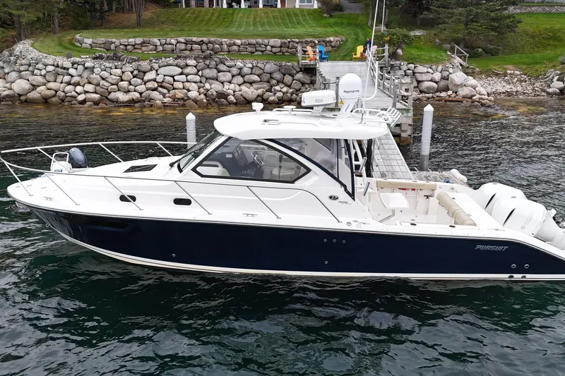  Yacht Photos Pics 2018 Pursuit OS 325 Offshore boat docked by rocky shoreline.