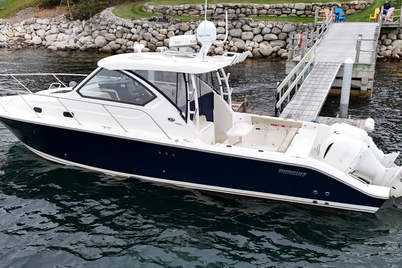  Yacht Photos Pics 2018 Pursuit OS 325 Offshore boat docked by a rocky shoreline.