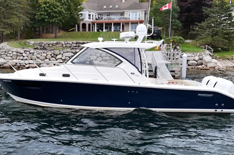  Yacht Photos Pics 2018 Pursuit OS 325 Offshore boat docked by a lakeside house with Canadian flag.