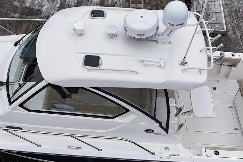  Yacht Photos Pics 2018 Pursuit OS 325 Offshore boat with radar and antennas, docked at a wooden pier.