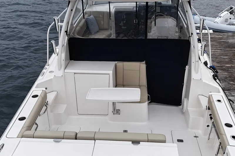  Yacht Photos Pics 2018 Pursuit OS 325 Offshore boat interior with seating and table, docked by the water.
