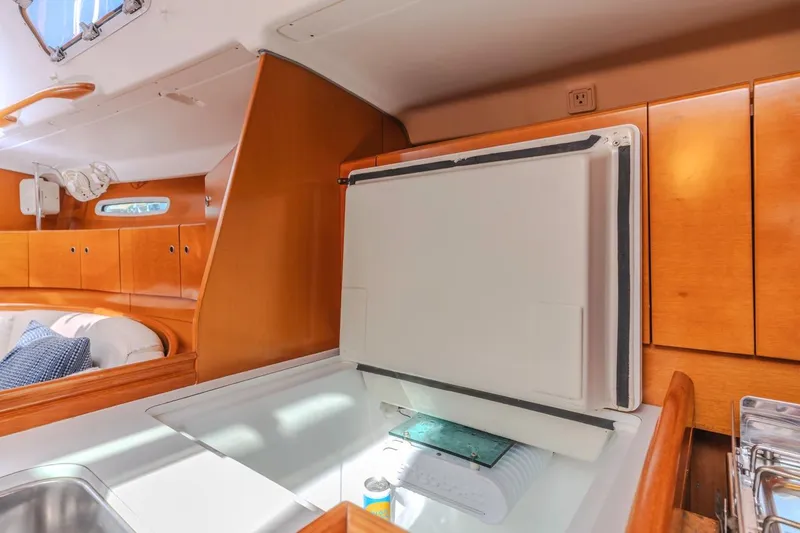 Sabbatical Yacht Photos Pics Interior of 2005 Beneteau First 44.7 yacht with wooden cabinetry and open fridge.