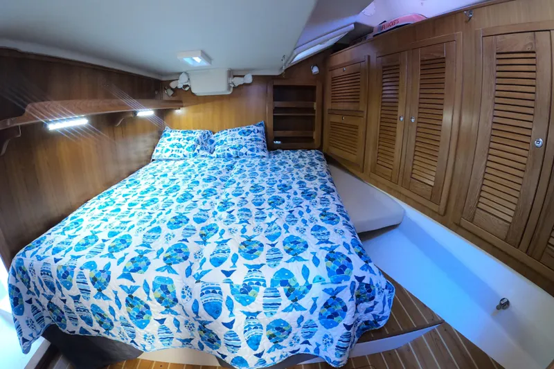  Yacht Photos Pics Cozy cabin interior of 2005 Catalina Morgan 440 with nautical-themed bedding and wooden cabinetry.