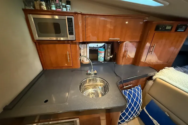 Valubelle Yacht Photos Pics 2012 Regal 35 Sport Coupe kitchen with microwave, sink, and wooden cabinets.