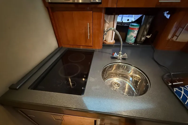 Valubelle Yacht Photos Pics Compact kitchen area in a 2012 Regal 35 Sport Coupe with sink and stovetop.