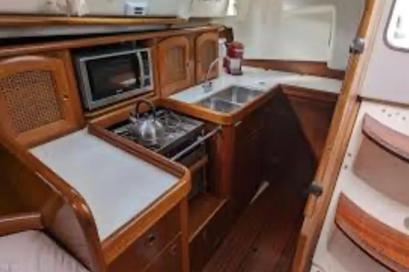  Yacht Photos Pics Interior of 2001 Beneteau Oceanis 411 yacht kitchen with stove, sink, and microwave.
