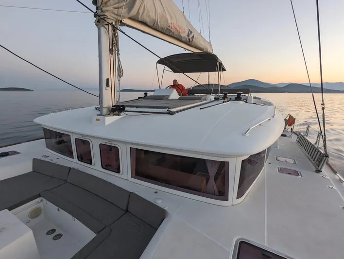 Yacht Photos Pics Lagoon 450 catamaran sailing at sunset, 2014 model, with scenic ocean and mountain backdrop.