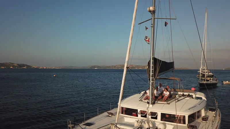  Yacht Photos Pics Lagoon 450 catamaran sailing on calm waters, 2014 model, with people relaxing on deck.
