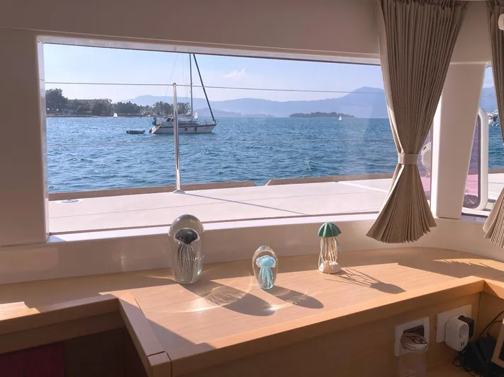  Yacht Photos Pics View from Lagoon 450 yacht window, showcasing ocean and sailboat, with decorative glass ornaments inside.