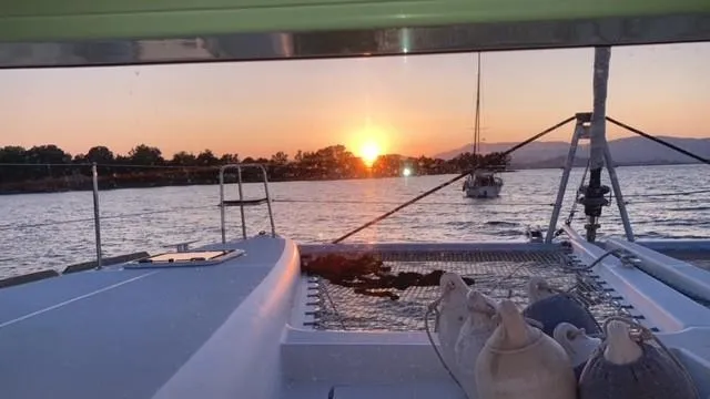  Yacht Photos Pics Lagoon 450 catamaran at sunset, 2014 model, with serene water and distant trees.