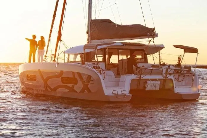 Yacht Photos Pics Manufacturer Provided Image: 2026 Excess 11 catamaran sailing at sunset with people on deck.