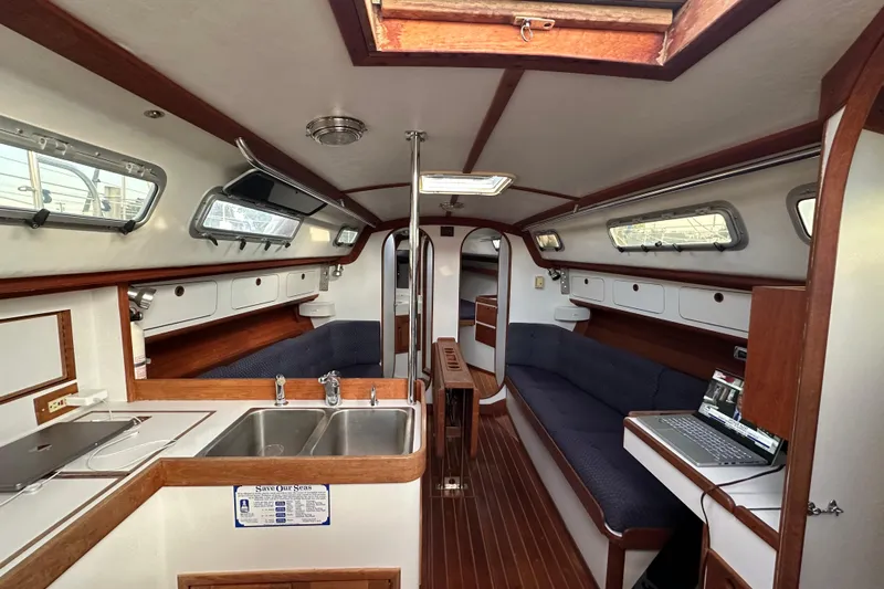 Grand Targee Yacht Photos Pics Interior of 1992 J Boats J/35 sailboat with kitchen, seating, and laptop workspace.