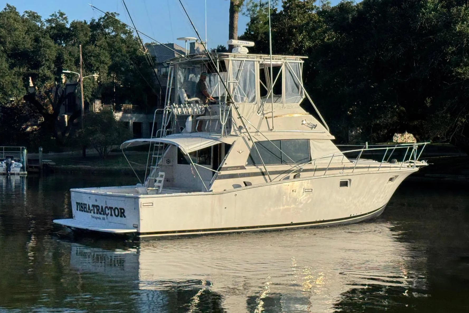 1979 Bertram 38 Convertible yacht on calm water, surrounded by trees.