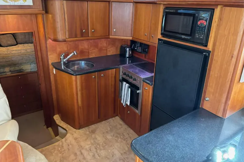 Just Blessed Yacht Photos Pics 2002 Silverton 43 Motor Yacht kitchen with wood cabinetry, sink, stove, microwave, and refrigerator.