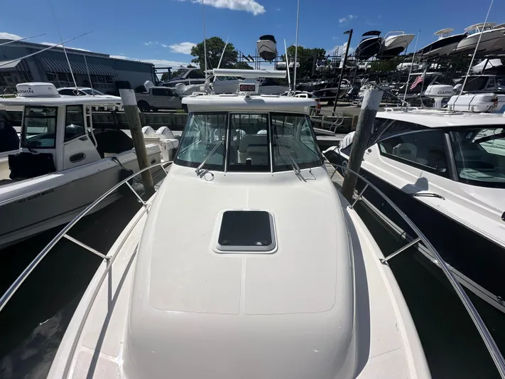  Yacht Photos Pics 2011 Pursuit OS 315 Offshore boat docked among other vessels under a clear blue sky.
