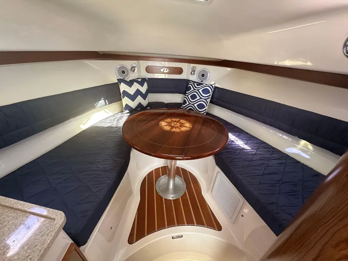  Yacht Photos Pics 2011 Pursuit OS 315 Offshore cabin with cushioned seating and wooden table.