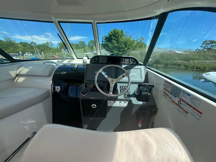  Yacht Photos Pics 2011 Pursuit OS 315 Offshore boat interior with steering wheel and dashboard, featuring large windows.