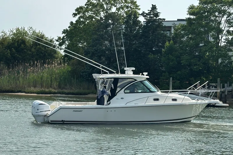  Yacht Photos Pics 2011 Pursuit OS 315 Offshore boat cruising on a calm waterway, surrounded by greenery.