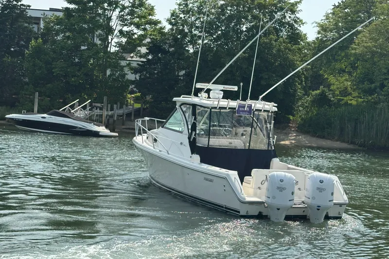 Yacht Photos Pics 2011 Pursuit OS 315 Offshore boat cruising near a wooded shoreline.