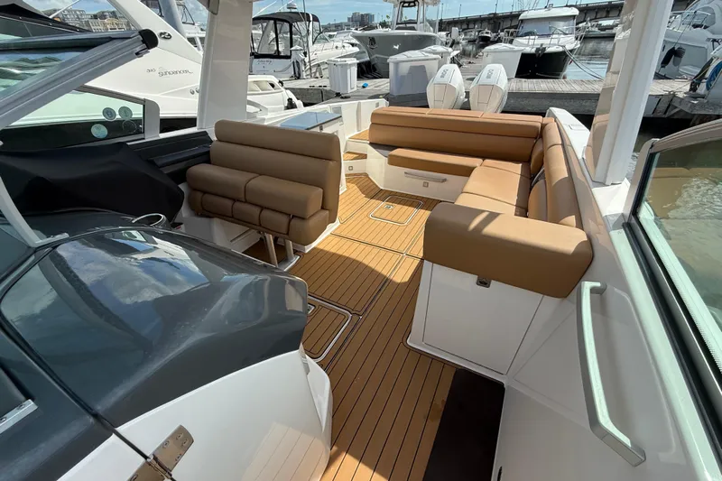 Yacht Photos Pics 2022 Aviara AV32 OB boat interior with tan seating and teak flooring at a marina.