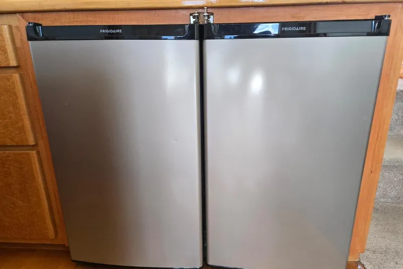  Yacht Photos Pics Stainless steel Frigidaire mini fridge with double doors in a wooden kitchen setting.
