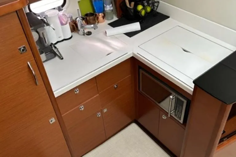  Yacht Photos Pics Compact kitchen area in a 2012 Prestige 440 S yacht with modern appliances and wooden cabinetry.