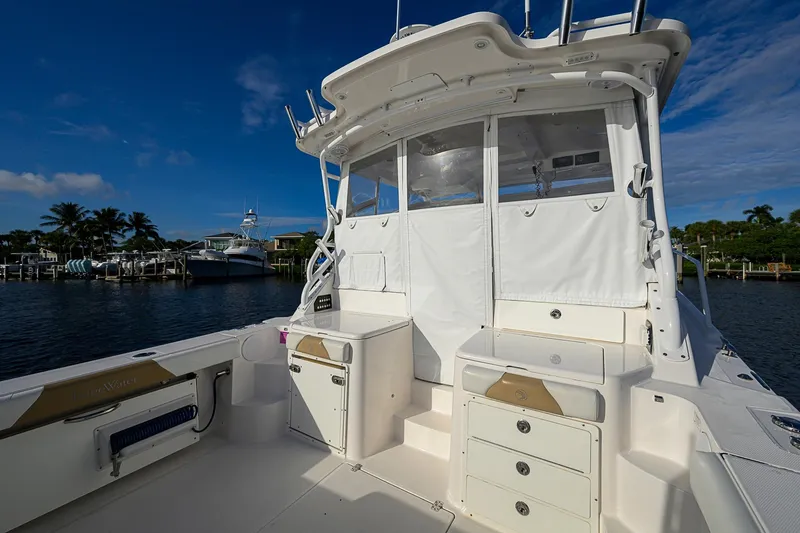  Yacht Photos Pics 2016 Edgewater 335 Express boat interior with storage, docked by palm trees and blue sky.