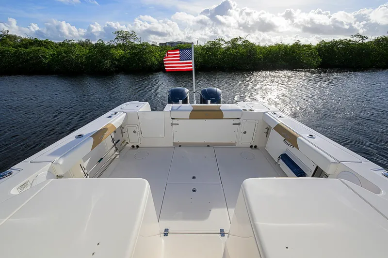  Yacht Photos Pics 2016 Edgewater 335 Express boat deck with American flag, calm water, and lush greenery.