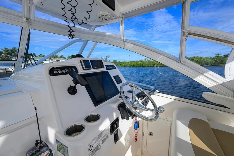 Yacht Photos Pics 2016 Edgewater 335 Express boat cockpit with steering wheel and navigation system, overlooking serene waters.