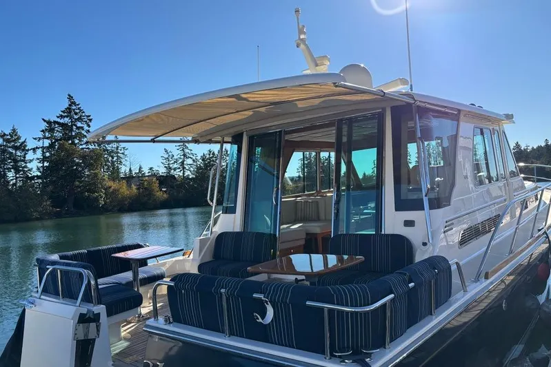 Salish Sky Yacht Photos Pics 2015 Sabre 54 Salon Express yacht with outdoor seating, docked by a scenic waterway.