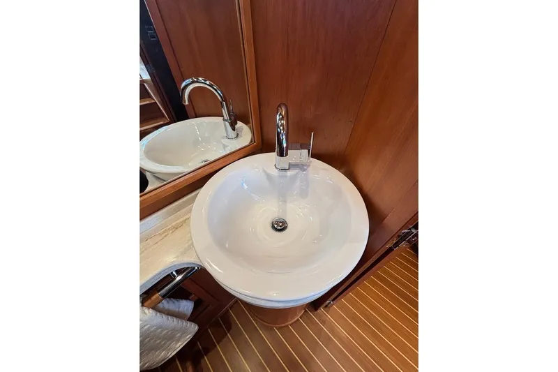 Salish Sky Yacht Photos Pics Bathroom sink in 2015 Sabre 54 Salon Express yacht, featuring wooden cabinetry and chrome faucet.