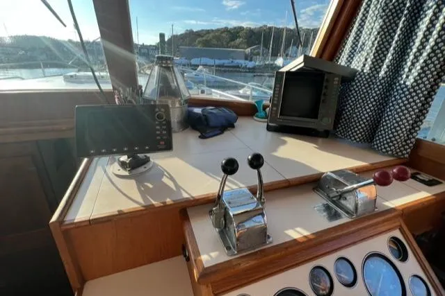 Slow Poke Yacht Photos Pics 1987 Grand Banks Classic Trawler helm with navigation equipment and controls, overlooking marina.