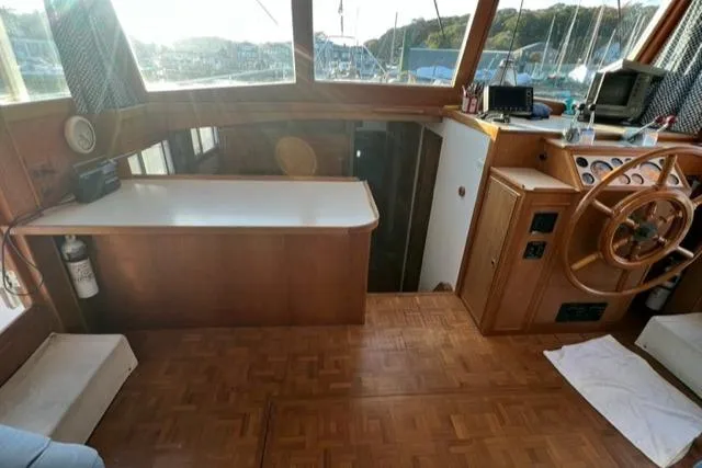 Slow Poke Yacht Photos Pics 1987 Grand Banks Classic Trawler interior with wooden helm, parquet flooring, and large windows.