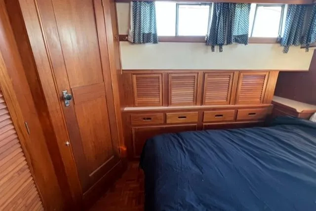 Slow Poke Yacht Photos Pics 1987 Grand Banks Classic Trawler bedroom with wooden cabinetry and blue bedding.