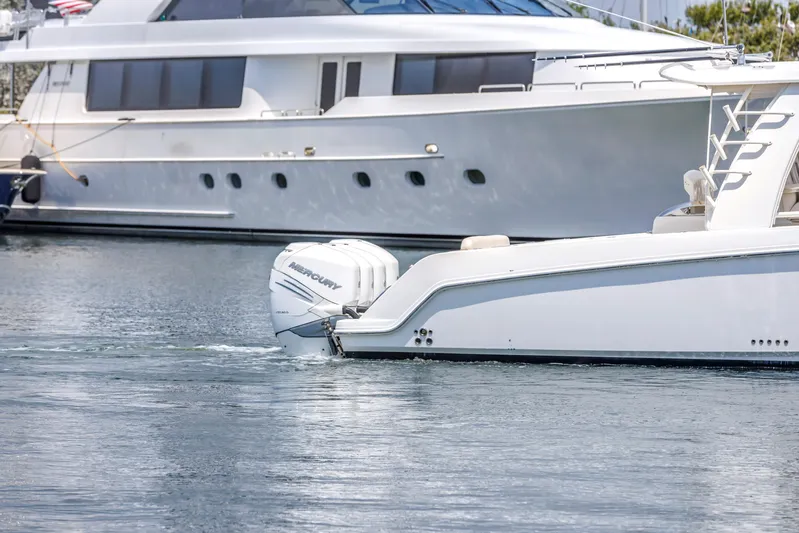  Yacht Photos Pics 2018 Boston Whaler 420 Outrage boat on water, with luxury yacht in background.