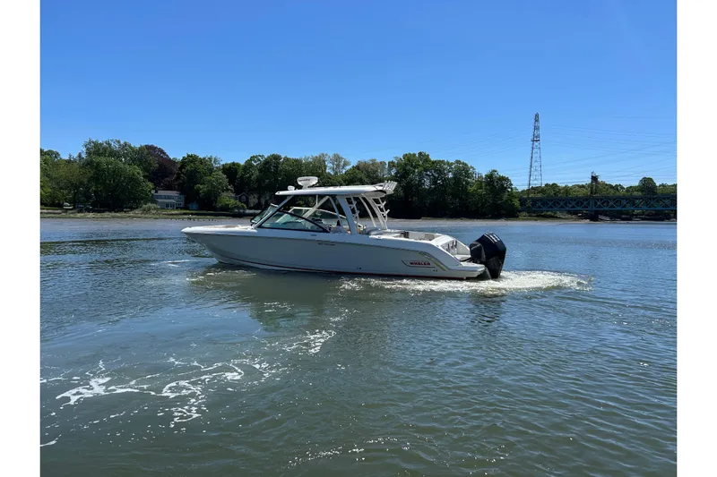  Yacht Photos Pics 2021 Boston Whaler 320 Vantage boat cruising on a calm river under a clear blue sky.