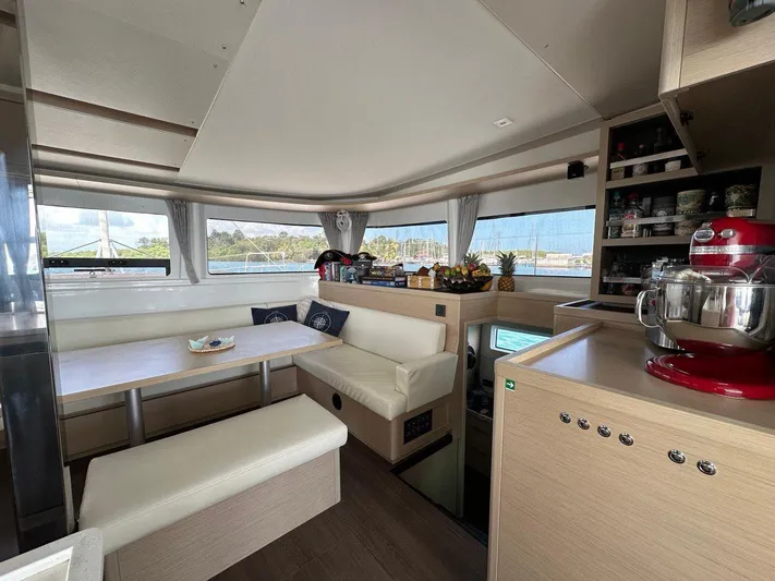 Uni Yacht Photos Pics Modern interior of 2023 Lagoon 46 catamaran with dining area and kitchen appliances.