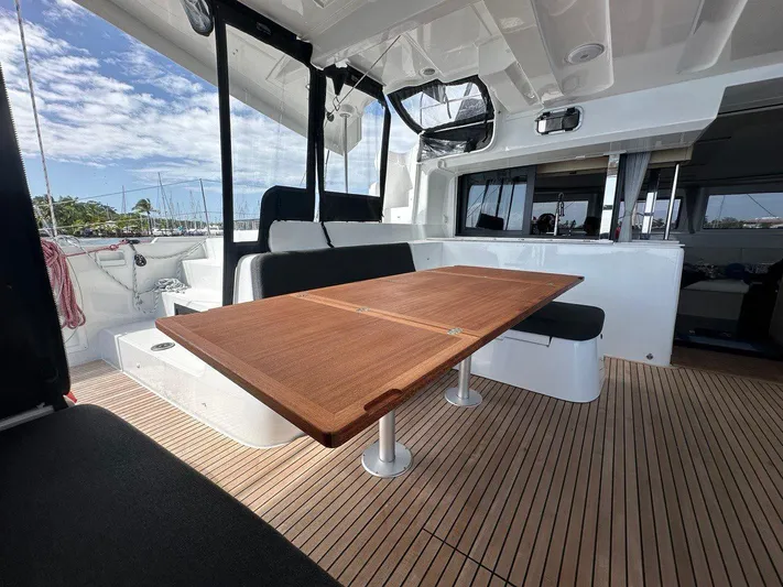 Uni Yacht Photos Pics 2023 Lagoon 46 yacht interior with wooden table and seating, showcasing modern design.