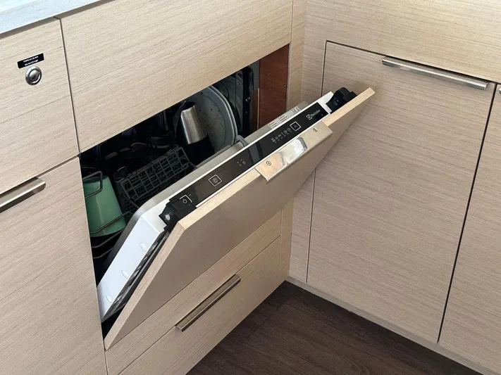 Uni Yacht Photos Pics Modern kitchen with partially open built-in dishwasher, light wood cabinetry, and dark flooring.