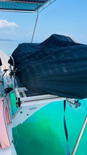 Uni Yacht Photos Pics 2023 Lagoon 46 yacht with covered equipment on deck, sailing in clear turquoise waters.